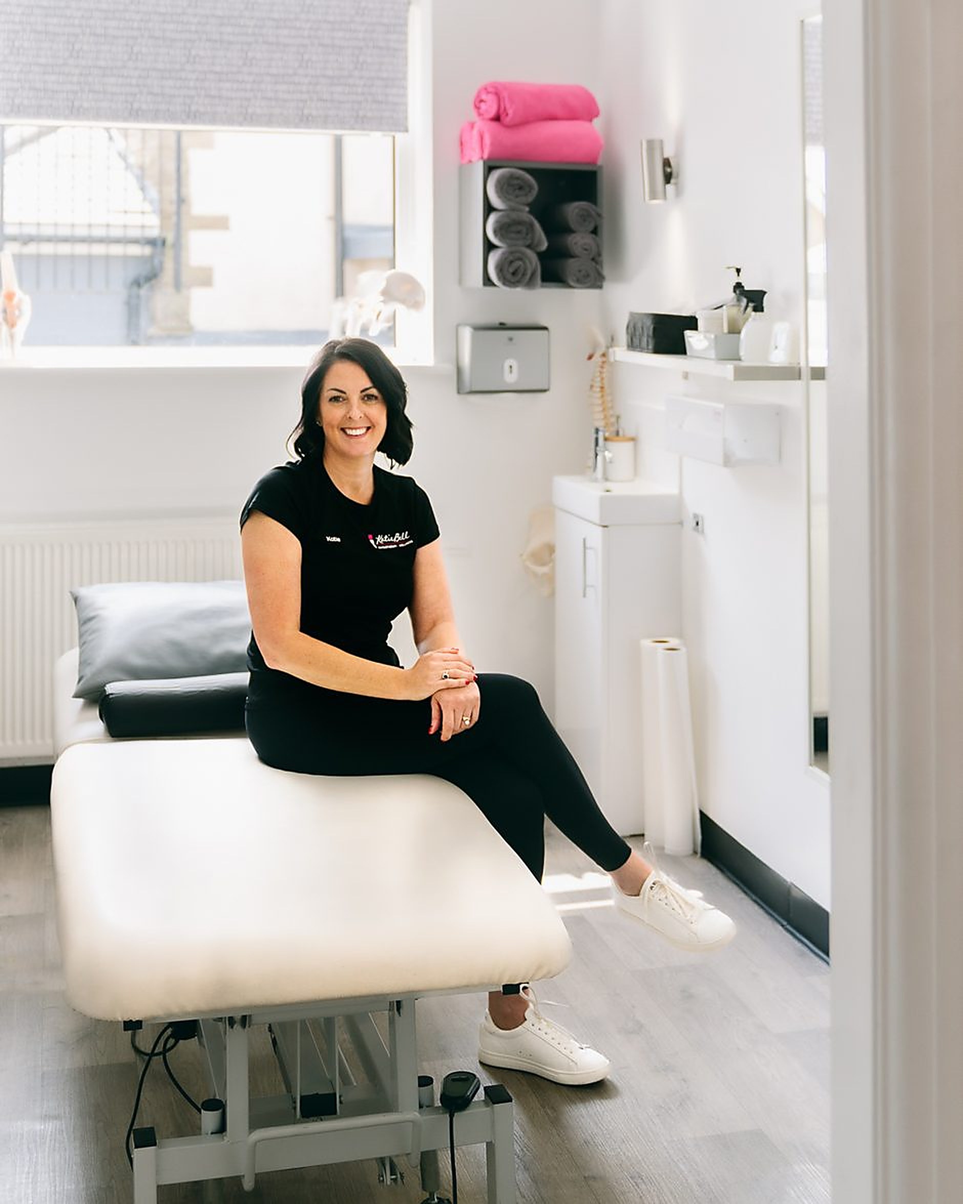 Katie Bell sitting on a treatment couch in her physio clinic